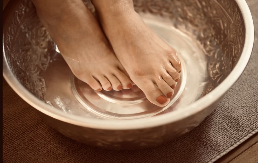 Warm foot ritual soak in a copper bowl at AURA Salon and Spa